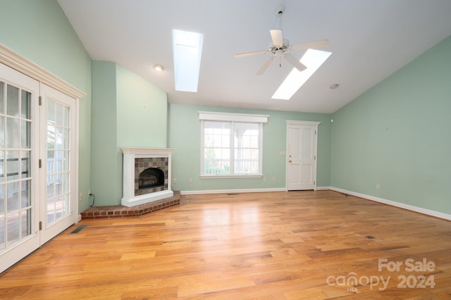 unfurnished living room with light wood-type flooring, ceiling fan, and vaulted ceiling with skylight