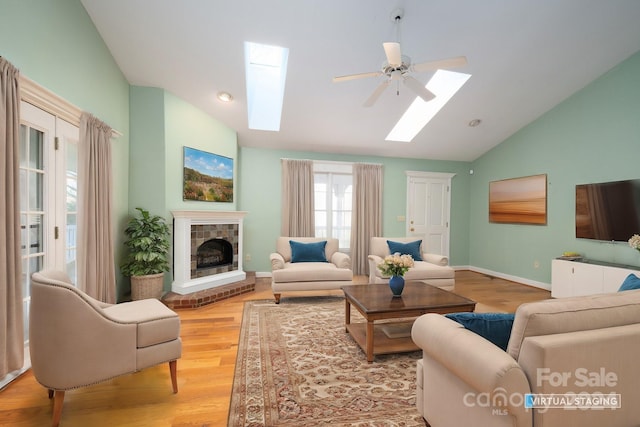 living room featuring ceiling fan, light wood-type flooring, and lofted ceiling with skylight