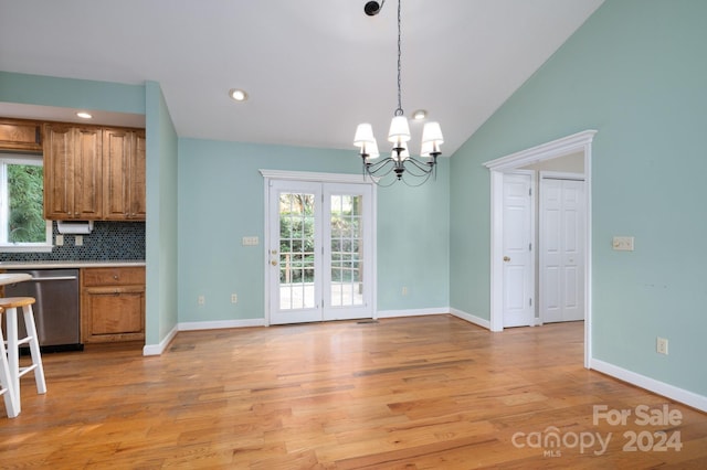 unfurnished dining area featuring light hardwood / wood-style floors, lofted ceiling, and a chandelier