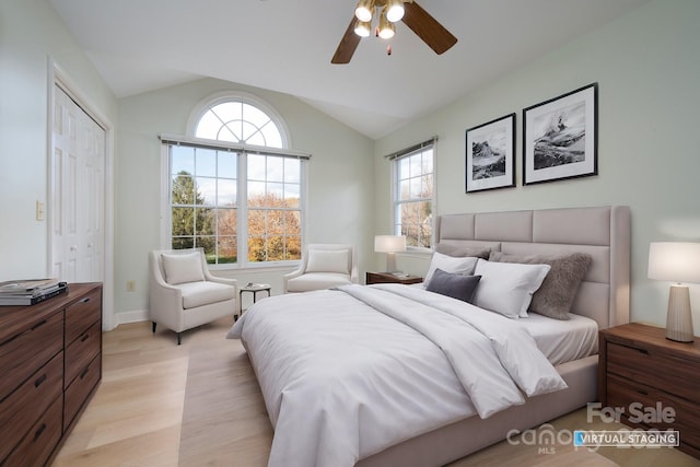 bedroom with light wood-type flooring, lofted ceiling, multiple windows, and a closet