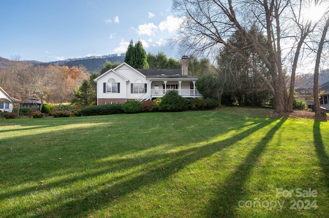 view of front of house featuring covered porch, a mountain view, and a front yard