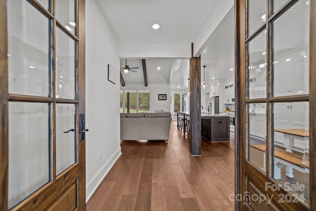 hallway with dark wood-type flooring and vaulted ceiling with beams