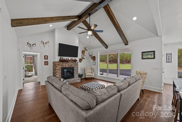 living room with a brick fireplace, a wealth of natural light, dark wood-type flooring, and beamed ceiling