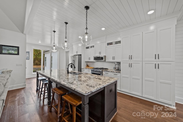 kitchen featuring a center island with sink, appliances with stainless steel finishes, pendant lighting, sink, and white cabinets