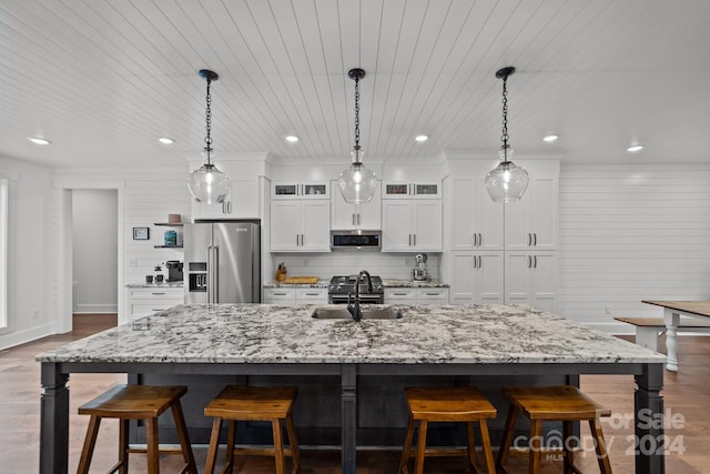 kitchen featuring decorative light fixtures, decorative backsplash, a large island with sink, and stainless steel appliances