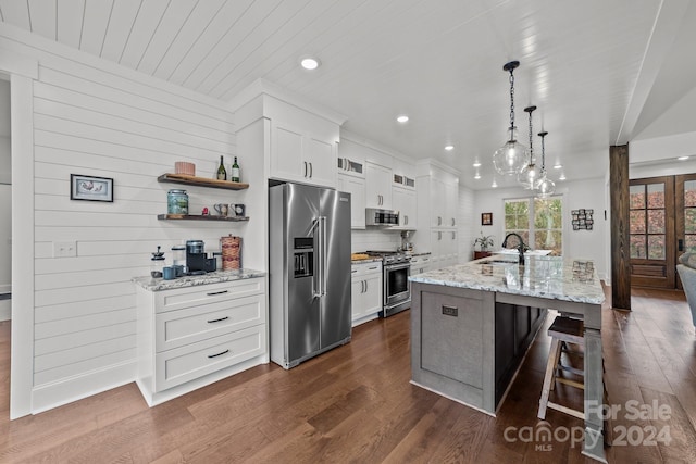 kitchen featuring white cabinets, stainless steel appliances, an island with sink, and dark hardwood / wood-style flooring