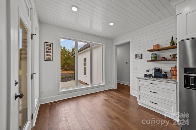 kitchen with dark hardwood / wood-style flooring, white cabinetry, stainless steel fridge with ice dispenser, and light stone countertops