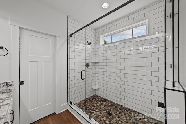 bathroom with hardwood / wood-style floors and a shower with shower door