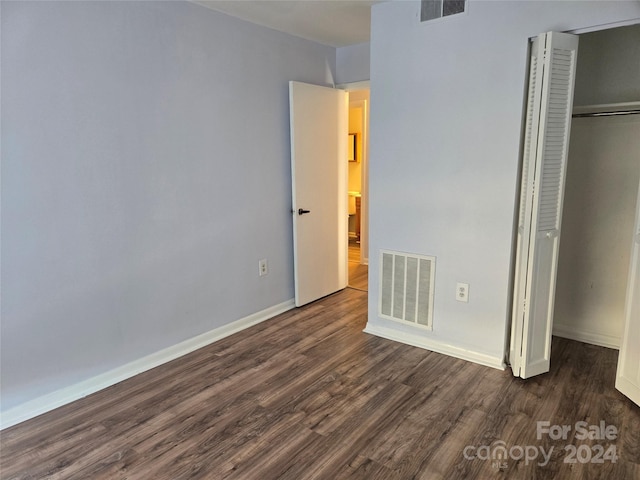 unfurnished bedroom featuring dark hardwood / wood-style flooring and a closet