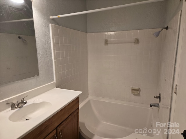 bathroom with tiled shower / bath combo and vanity