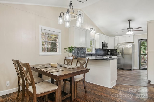 kitchen featuring hanging light fixtures, stainless steel appliances, kitchen peninsula, lofted ceiling, and white cabinets