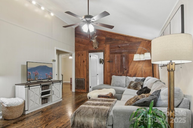 living room with wooden walls, dark hardwood / wood-style flooring, ceiling fan, and high vaulted ceiling