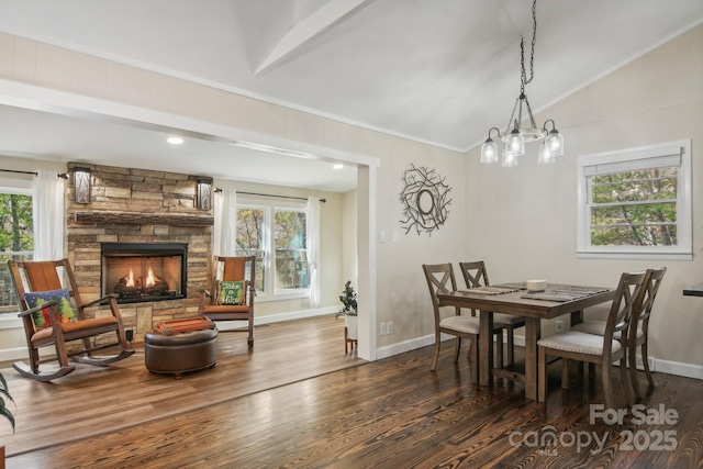 dining room featuring a healthy amount of sunlight, a fireplace, dark wood-type flooring, and lofted ceiling