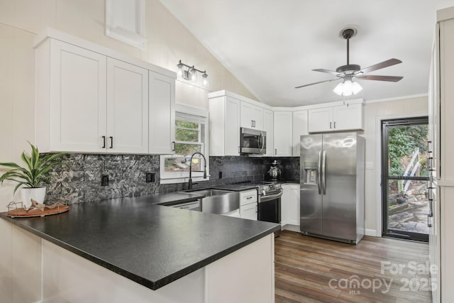 kitchen with kitchen peninsula, stainless steel appliances, white cabinetry, and lofted ceiling