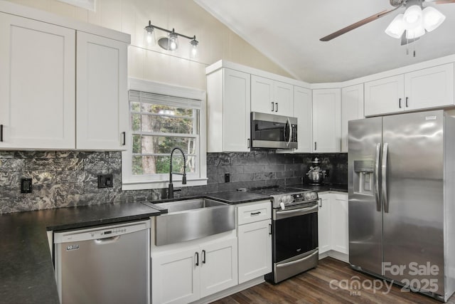 kitchen with dark hardwood / wood-style floors, white cabinetry, appliances with stainless steel finishes, and vaulted ceiling