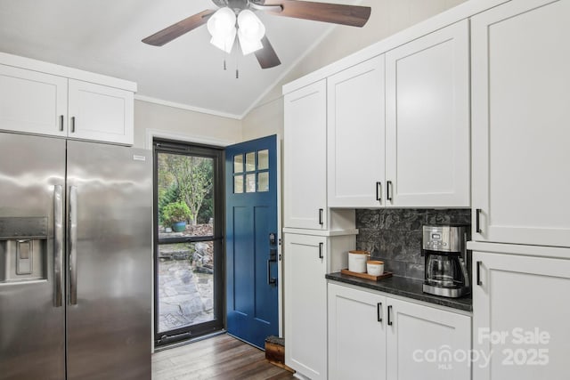 kitchen featuring stainless steel refrigerator with ice dispenser, vaulted ceiling, light hardwood / wood-style flooring, decorative backsplash, and white cabinetry