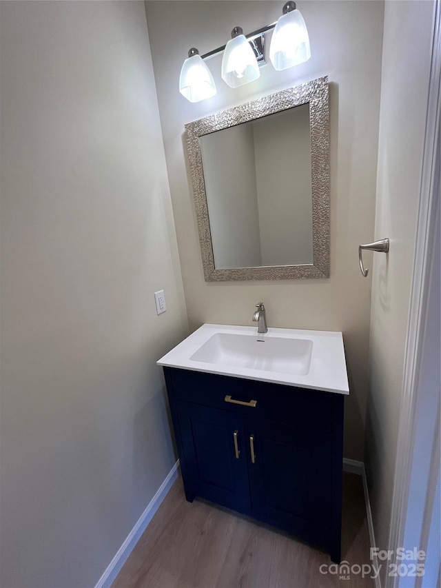 bathroom with baseboards, wood finished floors, and vanity