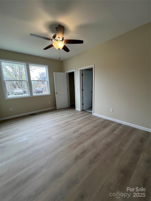 unfurnished bedroom with ceiling fan, light wood-type flooring, visible vents, and baseboards