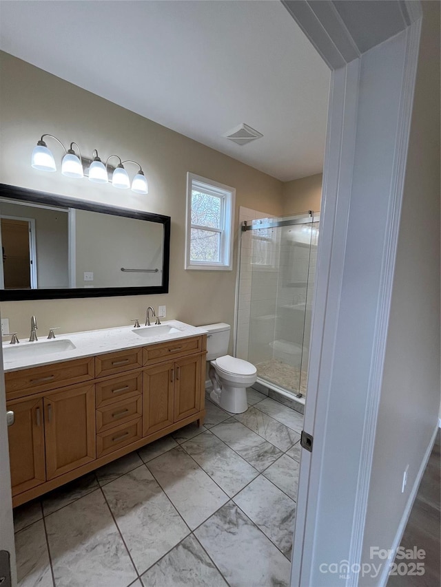 bathroom featuring vanity, a shower with shower door, and toilet