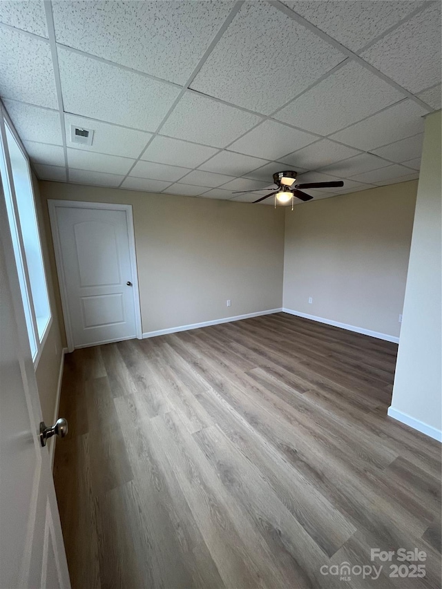 spare room with visible vents, baseboards, a drop ceiling, ceiling fan, and wood finished floors