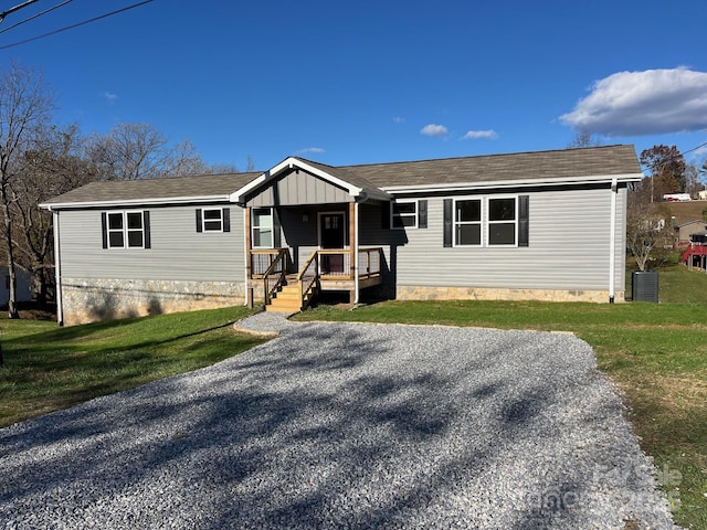 manufactured / mobile home with cooling unit, covered porch, and a front lawn