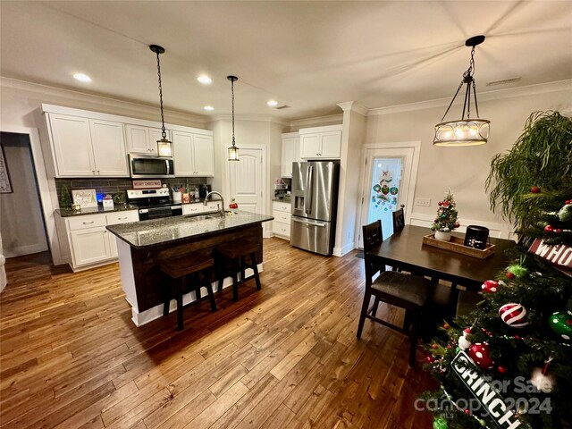 kitchen with stainless steel appliances, white cabinetry, and a kitchen island with sink