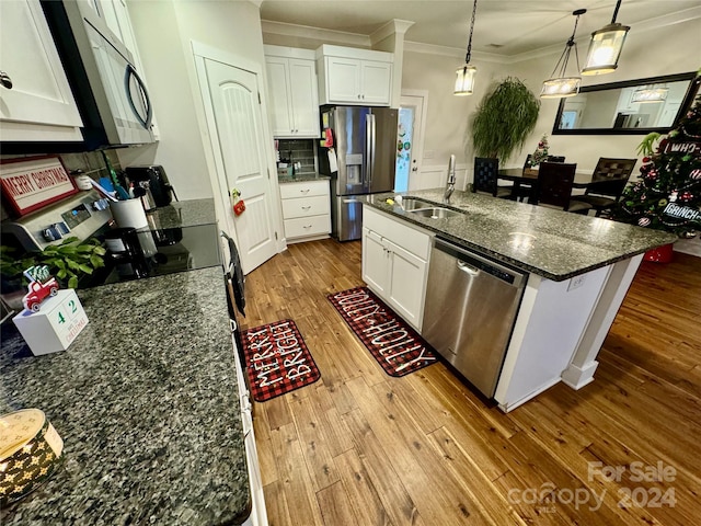 kitchen featuring white cabinets, hanging light fixtures, a center island with sink, and stainless steel appliances