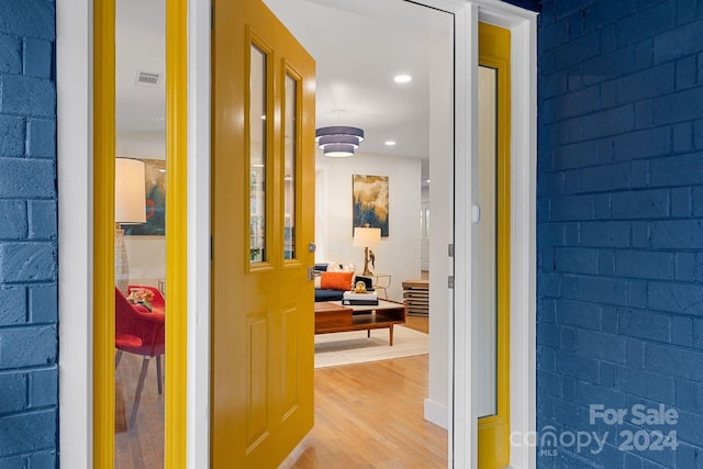 hall featuring brick wall and light hardwood / wood-style flooring