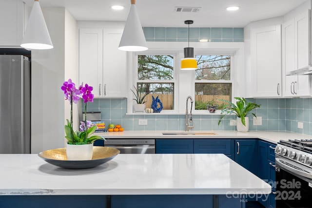 kitchen with appliances with stainless steel finishes, sink, blue cabinetry, white cabinetry, and hanging light fixtures