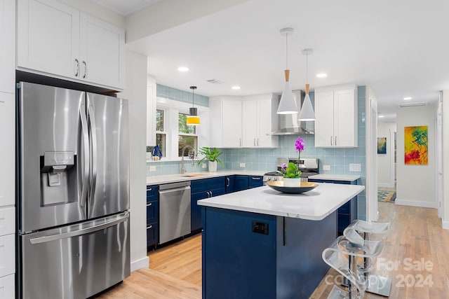 kitchen with white cabinets, appliances with stainless steel finishes, light wood-type flooring, and a kitchen island