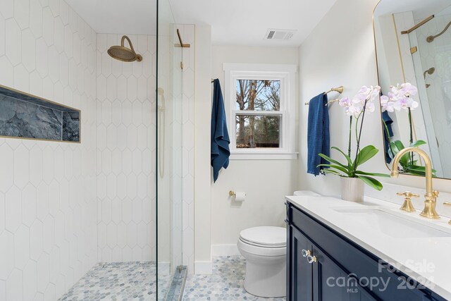 bathroom featuring tile patterned floors, vanity, toilet, and a tile shower