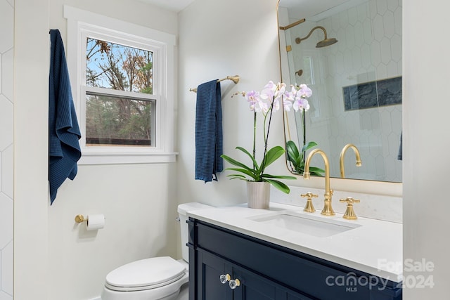 bathroom featuring a tile shower, vanity, and toilet