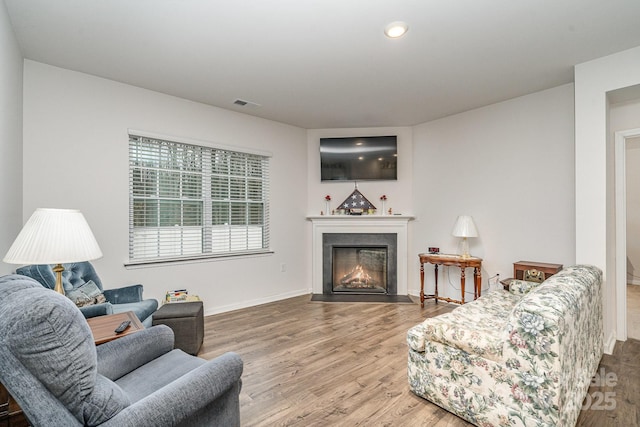 living area featuring visible vents, a fireplace with flush hearth, wood finished floors, and recessed lighting