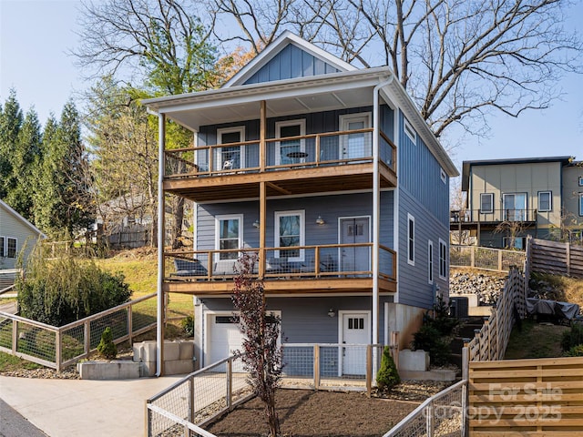 view of front of house featuring an attached garage, board and batten siding, fence, a balcony, and driveway