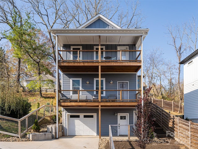 view of front of house featuring board and batten siding, a balcony, a garage, fence private yard, and driveway