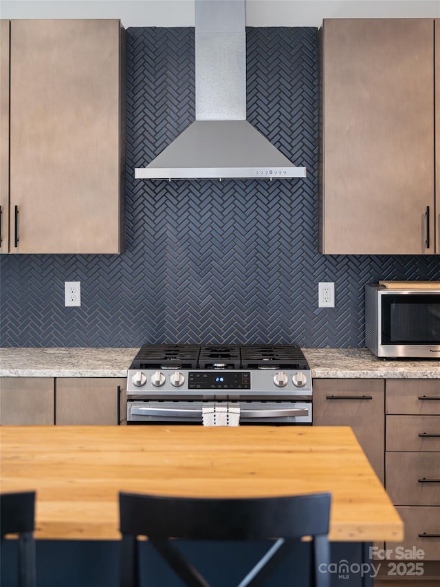 kitchen featuring stainless steel appliances, wooden counters, wall chimney range hood, and tasteful backsplash