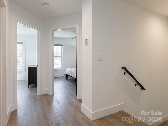 corridor featuring wood finished floors, an upstairs landing, and baseboards