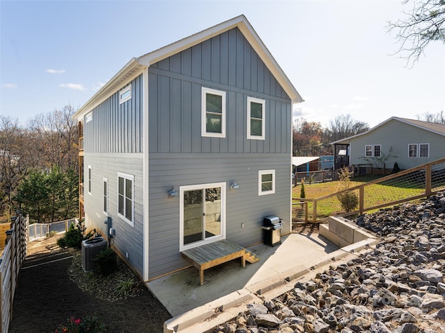 rear view of house featuring board and batten siding, a fenced backyard, and central AC unit