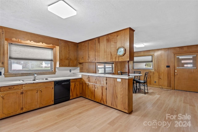 kitchen with wooden walls, sink, dishwasher, kitchen peninsula, and light hardwood / wood-style flooring