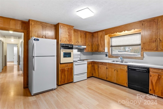 kitchen with a textured ceiling, light hardwood / wood-style flooring, sink, and white appliances