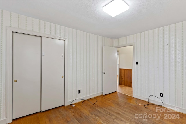 unfurnished bedroom with a closet, light wood-type flooring, and a textured ceiling