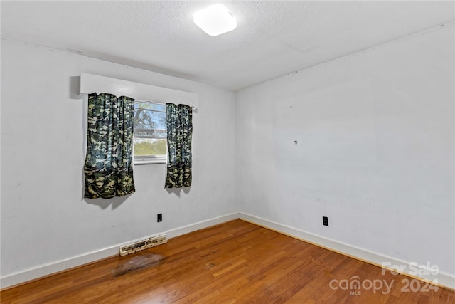 unfurnished room featuring wood-type flooring and a textured ceiling