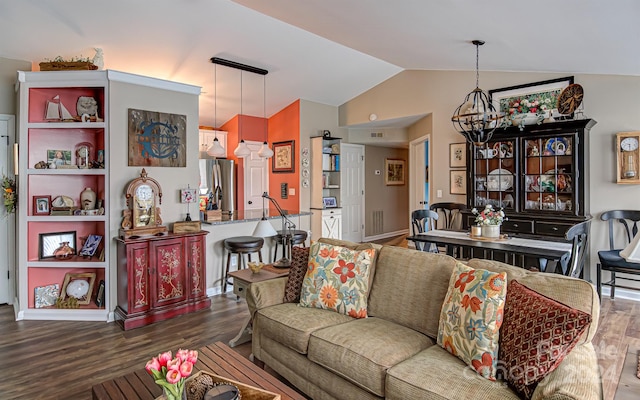 living room with dark hardwood / wood-style flooring, an inviting chandelier, and vaulted ceiling