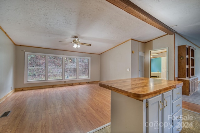 kitchen with wood counters, a center island, a textured ceiling, and light hardwood / wood-style flooring