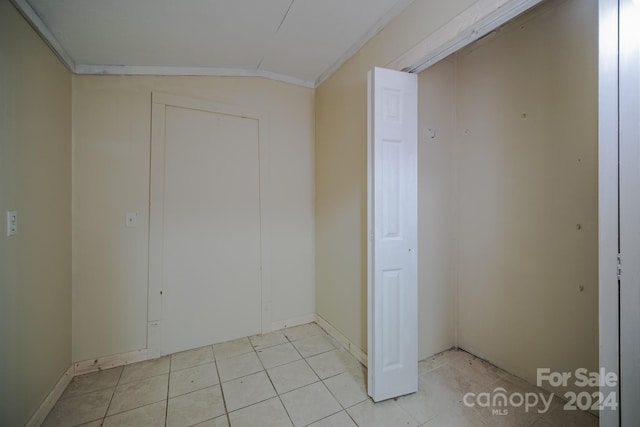 interior space featuring lofted ceiling, ornamental molding, and light tile patterned floors