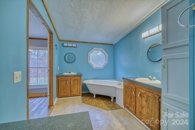 bathroom with vanity, a textured ceiling, a bathtub, and ornamental molding