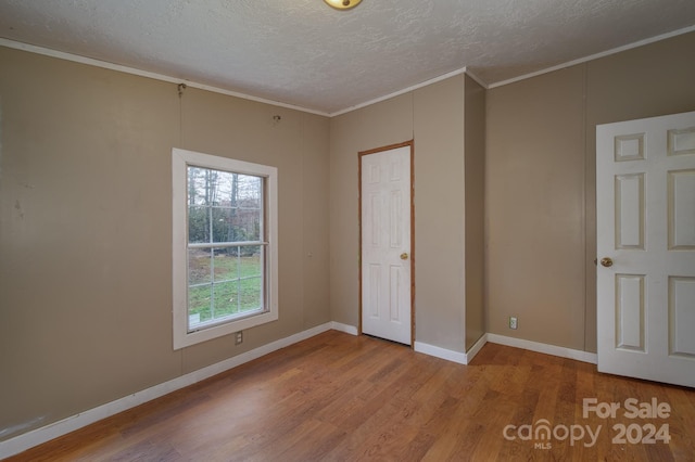 unfurnished bedroom with a textured ceiling, light hardwood / wood-style flooring, and ornamental molding