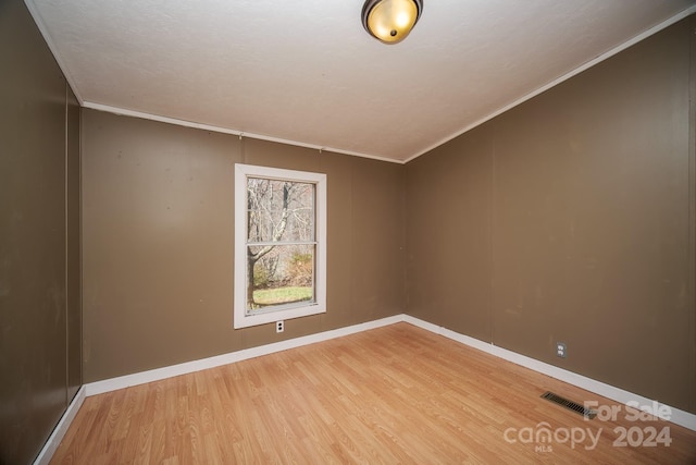 spare room featuring hardwood / wood-style flooring and crown molding