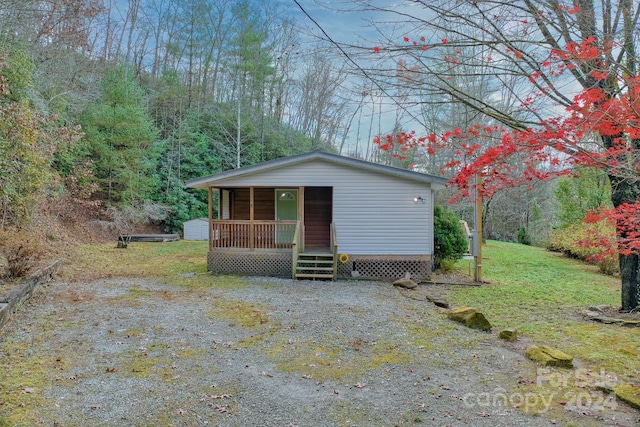 view of front of property with a front yard, a porch, and an outdoor structure