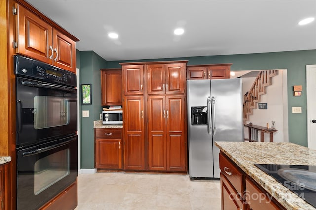 kitchen with light stone counters and black appliances